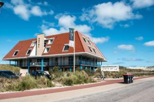 un bâtiment avec un toit orange sur le côté d'une route dans l'établissement Strandhotel Buren aan Zee, à Buren