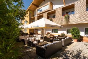 un patio con sofás y una sombrilla frente a un edificio en Der Winklhof, en Saalfelden am Steinernen Meer