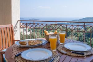 un tavolo in legno con piatti di cibo e bicchieri di succo d'arancia di Villa Sunny a Città di Skiathos