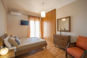 a bedroom with a bed and a chair and a mirror at Villa Sunny in Skiathos