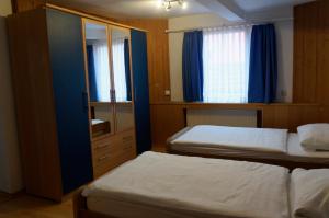 a bedroom with two beds and a cabinet with a mirror at Pension Burger - Bed & Breakfast in Weibersbrunn