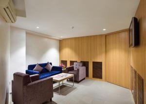 Hotel Leafio-Near Airport في مومباي: غرفة معيشة مع أريكة زرقاء وطاولة