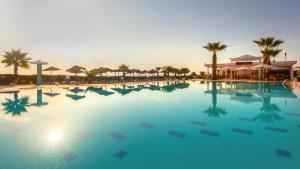 a large swimming pool with palm trees and umbrellas at Hotel Nour Congress & Resort in Bizerte