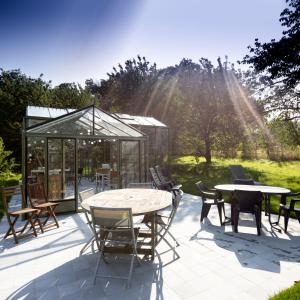 a patio with tables and chairs and a greenhouse at B&B Casa de Paja in Sint-Truiden