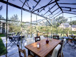 a conservatory with a wooden table and chairs at B&B Casa de Paja in Sint-Truiden