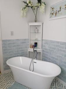 a white bath tub in a bathroom with blue tiles at Ambles in Northampton