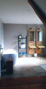 ein Badezimmer mit einer großen weißen Badewanne und Spiegeln in der Unterkunft Théière & Couverts - Les Chambres in Cernay