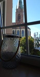 una ventana con vistas a una iglesia con una torre del reloj en Théière & Couverts - Les Chambres en Cernay