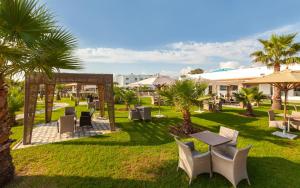 a resort yard with tables and chairs and palm trees at Hotel Nour Congress & Resort in Bizerte