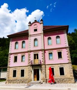 a pink building with a clock tower on top of it at La casa del popolo in Prato Carnico