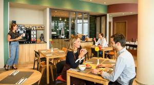 a group of people sitting at tables in a restaurant at Aparthotel Adagio Muenchen City in Munich