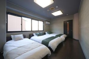 a row of three beds in a room with windows at Airstar Fukuoka Airport x Sakono building in Fukuoka