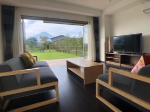 un soggiorno con una grande finestra e una TV di Kawaguchiko Urban Resort Villa a Fujikawaguchiko