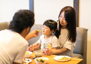 a woman and a woman sitting at a table with a child at Wow! KANAZAWA STAY in Kanazawa