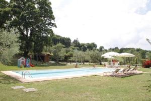 a swimming pool with chairs and umbrellas in a park at Le Fonti Di Santa Lucia in San Gimignano