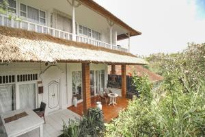 ein Haus mit einem Strohdach und einer Terrasse in der Unterkunft Taman Indrakila in Ubud