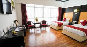 Cette chambre d'hôtel comprend deux lits, une table et des chaises. dans l'établissement Juffair Gate Hotel, à Manama