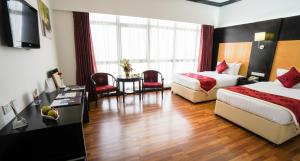 ein Hotelzimmer mit 2 Betten, einem Tisch und Stühlen in der Unterkunft Juffair Gate Hotel in Manama