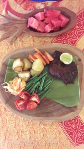 a plate of food with meat and vegetables on a table at Marind Dive Eco Resort Wakatobi in Waha
