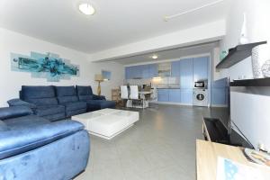 ein Wohnzimmer mit einem blauen Sofa und einer Küche in der Unterkunft Beautiful Coral and Ocean Blue Apartments in Oceano Atlantico in Portimão