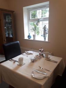 a table with a white table cloth and a window at Berry House Bed & Breakfast in Littlehampton