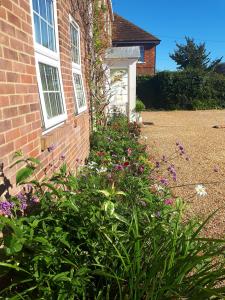 una casa de ladrillo con un jardín de flores delante de ella en Berry House Bed & Breakfast, en Littlehampton