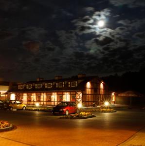 a building with cars parked in a parking lot at night at Gościniec Rutikal in Sianów