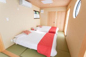 two beds in a small room with a window at Kabuku Resort in Shima