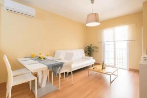ein Wohnzimmer mit einem Tisch und einem weißen Sofa in der Unterkunft Shiny Lud Family Apartment in Málaga