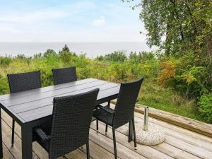 a wooden table and chairs on a deck with the ocean at 6 person holiday home in Knebel in Knebel