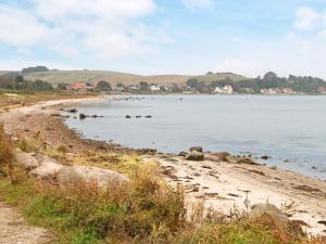 a beach with rocks in the water with hills in the background at 8 person holiday home in Knebel in Knebel