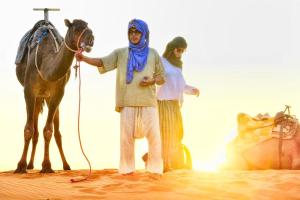 a man and a woman with a horse in the desert at Isma Luxury Camp in Merzouga