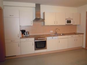 a kitchen with white cabinets and a sink and a stove at Appartements NEUStockach in Gerlos +37 photos