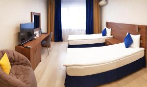 コヴロフにあるOLIMPIA DeLuxeのベッド2台とテレビが備わるホテルルームです。