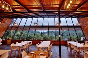 ein Restaurant mit Tischen und Stühlen und einem großen Fenster in der Unterkunft Le Villagio Resort & Domes in Sultan Bathery
