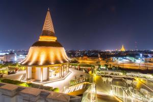 um grande edifício com um campanário numa cidade à noite em Mida Grande Hotel Dhavaravati Nakhon Pathom - SHA PLUS em Nakhon Pathom