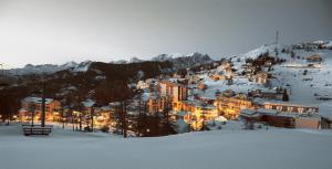 una ciudad en la nieve en las montañas por la noche en Vacancéole - Résidence Les Gorges Rouges, en Guillaumes