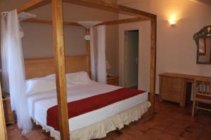 1 dormitorio con cama con dosel y escritorio en Hotel La Posada De Alameda, en Alameda del Valle