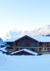 un edificio cubierto de nieve con montañas de fondo en Vacancéole - Résidence Grand Massif, en Morillon