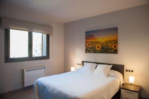 a bedroom with a white bed and a painting of sunflowers at WinTuWin Apartments in Rialp