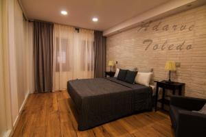 a bedroom with a bed and a brick wall at Apartamentos Adarve Toledo in Toledo