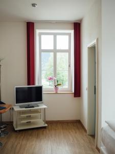uma sala de estar com uma televisão e uma janela em Hotel Garni Ammergauer Hof em Oberammergau