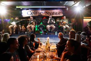 a group of people sitting at a table in a bar with musicians at Arlington Hotel O'Connell Bridge in Dublin