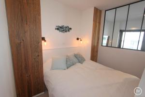 ein kleines Schlafzimmer mit einem weißen Bett und einem Fenster in der Unterkunft Lily a la mer du Zoute in Knokke-Heist
