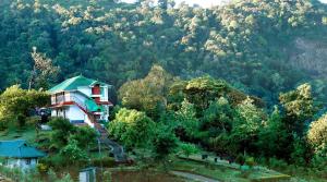 una casa en la cima de una colina con un bosque en Camelot Resort, en Munnar