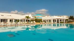 a large swimming pool with chairs and buildings at Hotel Nour Congress & Resort in Bizerte