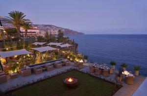 an outdoor restaurant with a view of the ocean at night at Les Suites at The Cliff Bay - PortoBay in Funchal