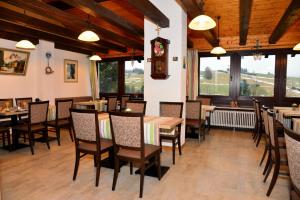 a dining room with tables and chairs and windows at Hotel garni Siebenstern in Bischofsgrün