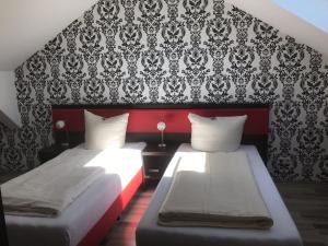 two beds in a bedroom with a red and black wall at Cityhotel Ahlen Garni in Ahlen