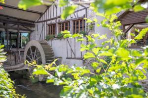 una casa vieja con una rueda de agua delante de ella en Le Moulin Du Landion Hôtel et Spa en Dolancourt